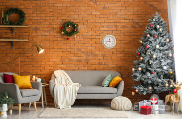 Stylish interior with Christmas tree by sofa and clock on brick wall