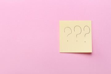 Sticky note with question marks on pink background