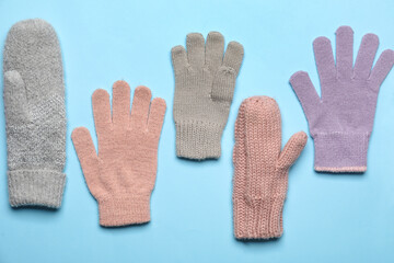 Different mittens and gloves on color background