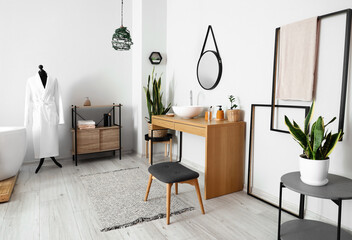 Interior of light bathroom with sink, mirror and mannequin