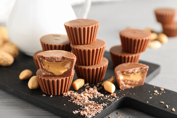 Board with tasty peanut butter cups on table