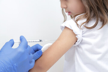 Criança tomando vacina no braço com prevenção do covid 19 e medico com luva azul e seringa na...