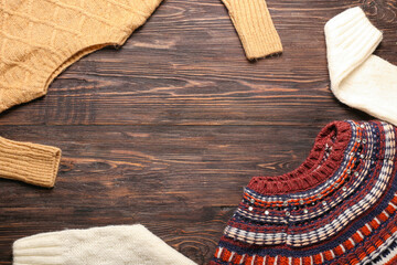 Warm stylish sweaters on wooden background