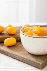 Bowl of tasty kumquat jam and fresh fruits on kitchen table