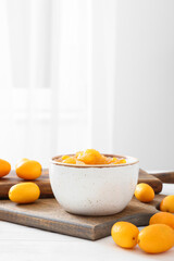 Bowl of tasty kumquat jam and fresh fruits on kitchen table