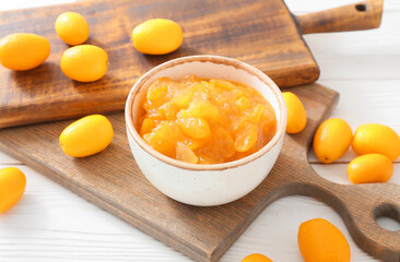 Bowl of tasty kumquat jam and fresh fruits on white wooden background