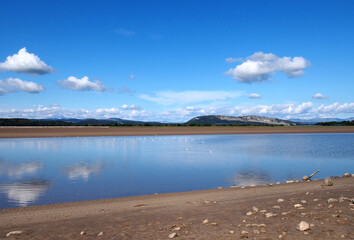 the river kent in cumbria with with lake district hills in the distance and clouds reflected in the water