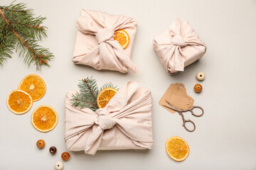 Christmas gifts wrapped in fabric on light background