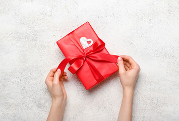 Female hands with gift box for Valentine's Day on light background