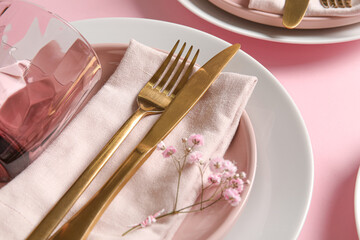 Festive stylish table setting with flowers on pink background, closeup
