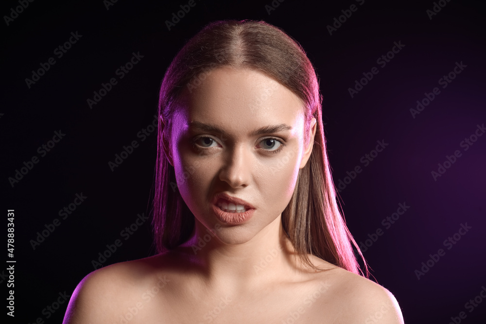 Wall mural Toned portrait of angry young woman on black background