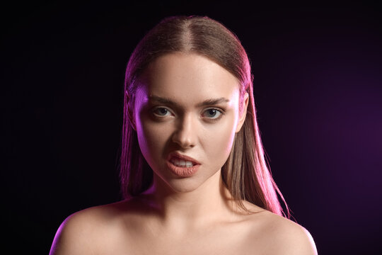 Toned portrait of angry young woman on black background