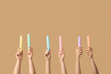 Hands with popular pop tubes on color background