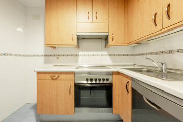 Fototapeta premium Kitchen with beech wood-tone furniture, white countertop and valance between the tiles