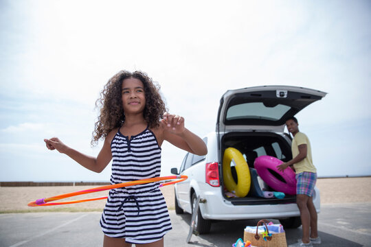 Girl spinning plastic hoop outside van at beach