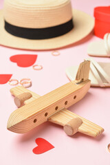 Wooden airplane, paper hearts, hat, rings and shoes on pink background, closeup. Valentine's Day celebration