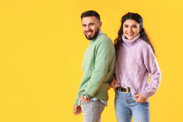 Obraz premium Happy young couple in warm sweaters on color background