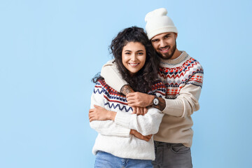 Happy young couple in warm sweaters on color background