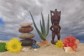 Tiki Statue on Sand With Flowers and Sea Shells