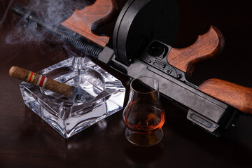 Vintage Thompson submachine gun on a dark brown table with a cigar and whiskey 