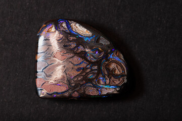 Colorful boulder opal gem from Koroit Australia on black background