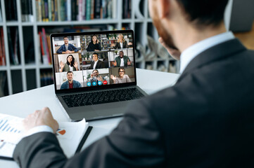 Distant communication. Busy man using a laptop, conducts virtual meeting with business partners on...