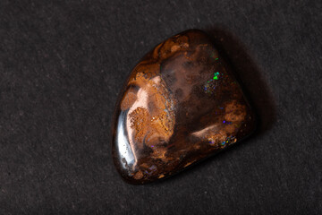 Colorful boulder opal gem from Koroit Australia on black background