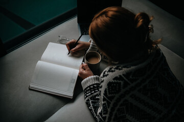 woman drinking coffee and taking notes in her diary