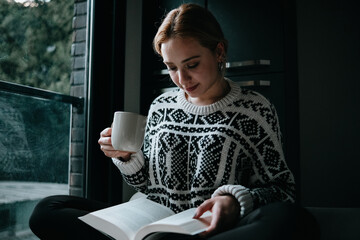 woman reading a book while drinking coffee