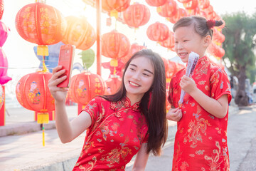 Chinese woman and child wearing traditional dress taking their photo by mobile phone,Chinese new year concept.