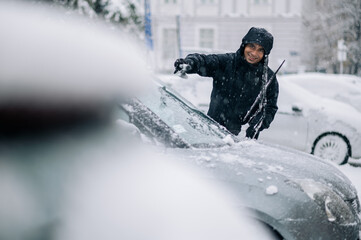 Fototapeta na wymiar Middle aged man cleaning car from snow and ice