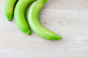 Three green bananas on a wooden background Healthy eating. Top left corner. Fresh banana fruit, ripe banana, Bunch of bananas. Copy space