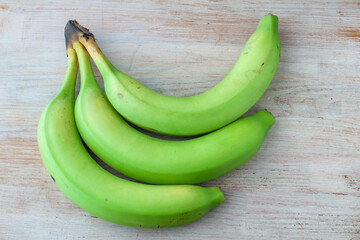 Three green bananas on a wooden background Healthy eating. Fresh banana fruit, ripe banana, Bunch of bananas. Copy space. Vegetarian
