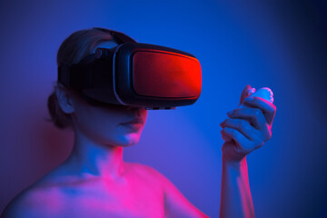 Woman wearing VR glasses and spending time controlling with joystick, studio photo with colorful glow