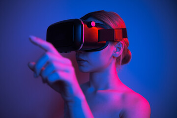 woman in vr glasses stretching her finger to touch something in virtual world