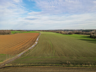 Fototapeta na wymiar Areal view of agricultural field against cloudy sky in south of Belgium.