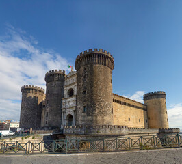 Fototapeta na wymiar Wide view of the New Castle (Castel Nuovo) in Naples, Italy, in the sunny winter day, with white clouds in the blue sky