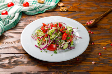 Vegetable salad with tomatoes and cucumbers on wooden table