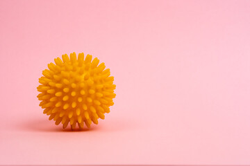 yellow ball of a massage needle on a pink background, the concept of prevention of flat feet, hallux valgus, copy space