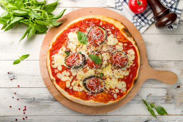 pizza with eggplant, cheese, basil and tomato sauce top view on white woden table