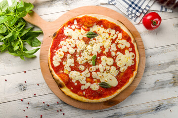 Italian pizza Margherita with tomato sauce and basil on white wooden table