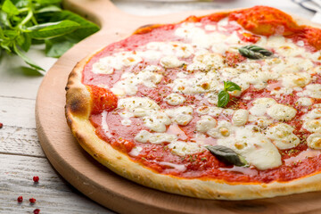 Italian pizza Margherita with tomato sauce and basil on white wooden table close up