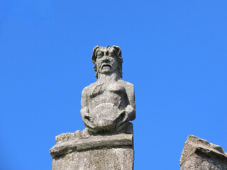 Fototapeta na wymiar Medieval stone sculpture on top of Monkbar gate of York city wall. Blue sky background