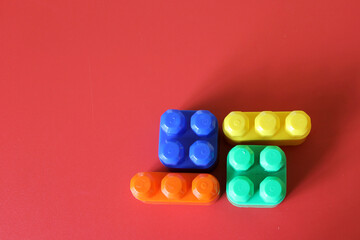 Pieces of plastic rainbow multicolored buildable toy blocks formed and arranged on red background