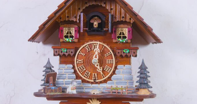 Man adjusts cuckoo clock hands of creative vintage house-shaped wall clock with swinging pendulum to cuckoo on wall AT home closeup
