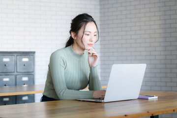 Asian women thinking with serious expressions while looking at the computer.