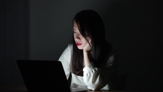 暗い部屋でパソコンを使う女性