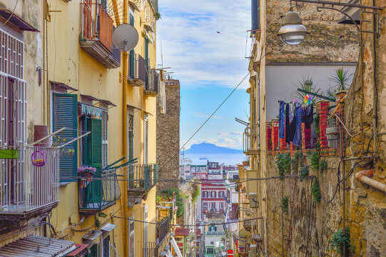 Typical street of Naples old town: narrow, steep, delapidated, picturesque, with jalousies on windows, flower pots and drying laundry