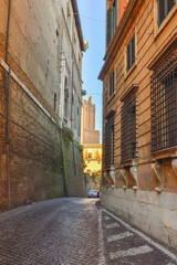 Fototapeta na wymiar Paved road, old houses and blue sky in a sunny winter day on Via Panisperna in Rome, Italy