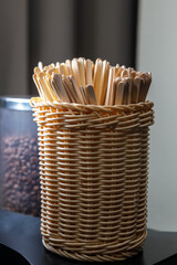 Wooden stirring sticks are in a wicker basket.